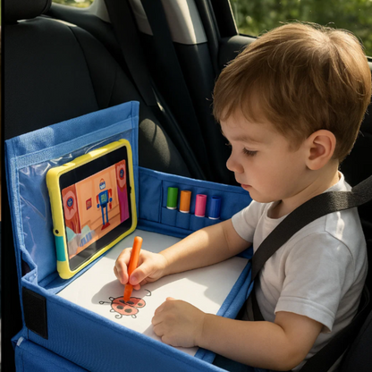Enfant installé dans un siège auto, dessinant sur la surface tableau blanc du plateau de voyage pendant que la tablette diffuse un dessin animé