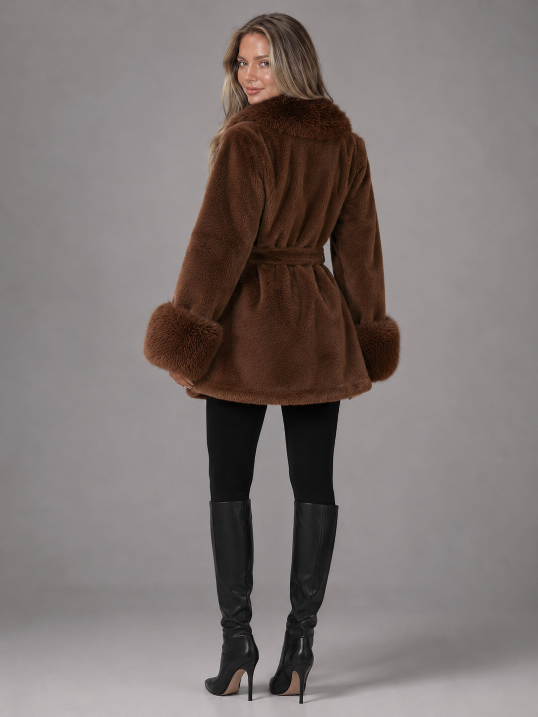 Manteau à ceinture pour femme avec col en fausse fourrure, modèle portant le manteau de profil