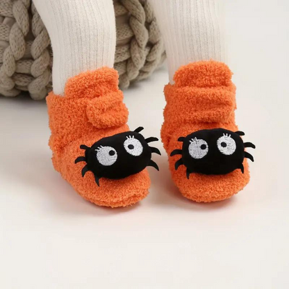 Chaussons Halloween enfant coloris orange, portés aux pieds d'un enfant
