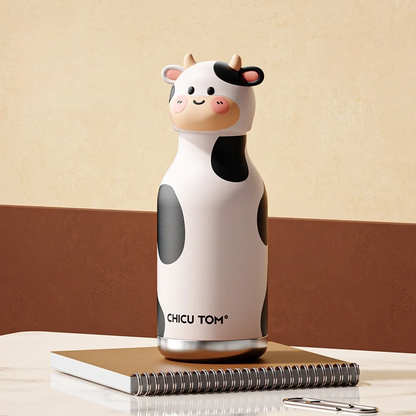 Gourde design vache à motif tacheté noir et blanc posée sur un cahier