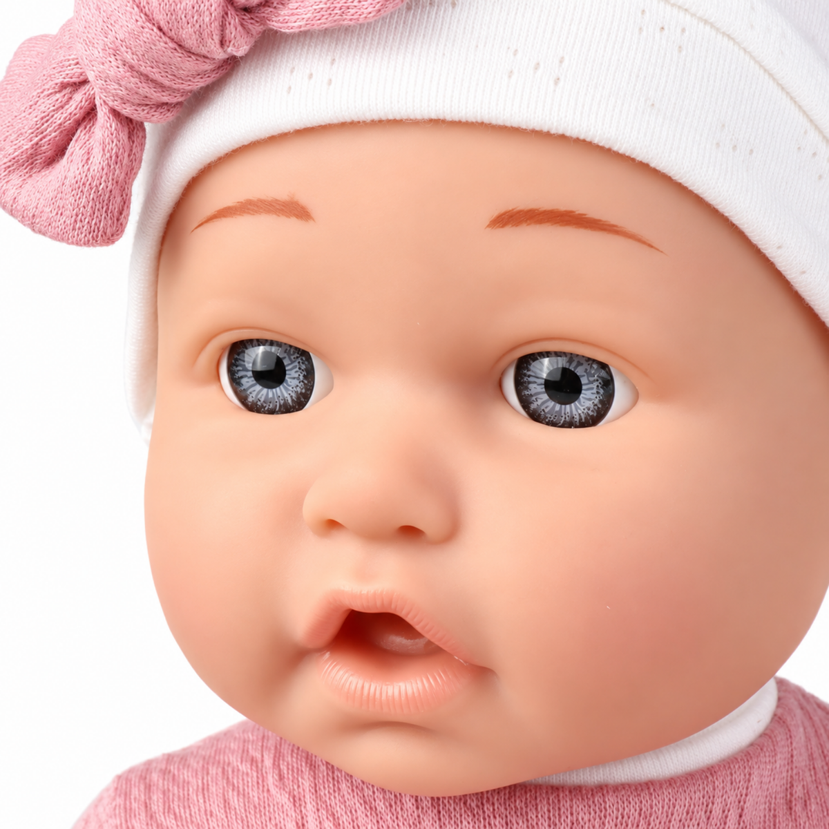 Gros plan du visage du poupon portant un bonnet blanc à nœud rose
