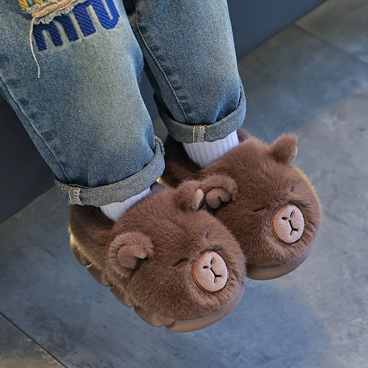 Enfant portant les chaussons capybara en peluche à l'intérieur