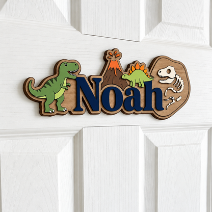 Plaque prénom dinosaure en bois avec lettrage bleu marine, volcan et squelette