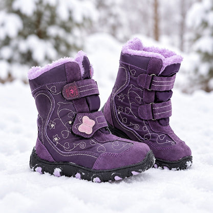 Enfant portant des bottes de neige violettes à imprimé papillon, en extérieur dans la neige