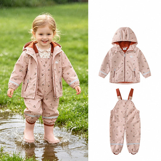 Fillette en ensemble de pluie imperméable imprimé fleuri rose, veste à capuche et salopette, jouant dans une flaque, avec l'ensemble présenté à plat