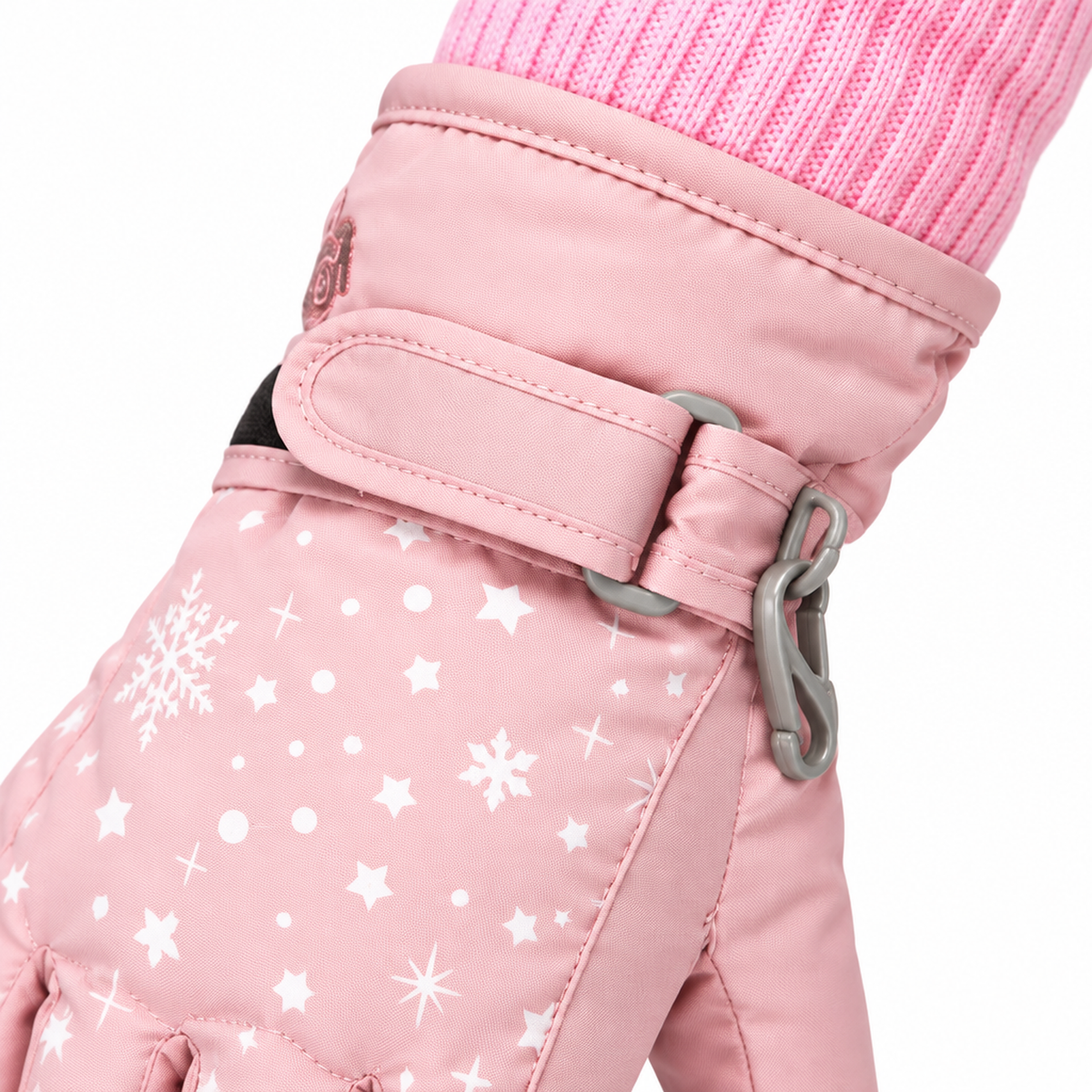 Gros plan sur la sangle de poignet ajustable avec clip anti-perte fixée sur le gant de ski rose clair pour fille