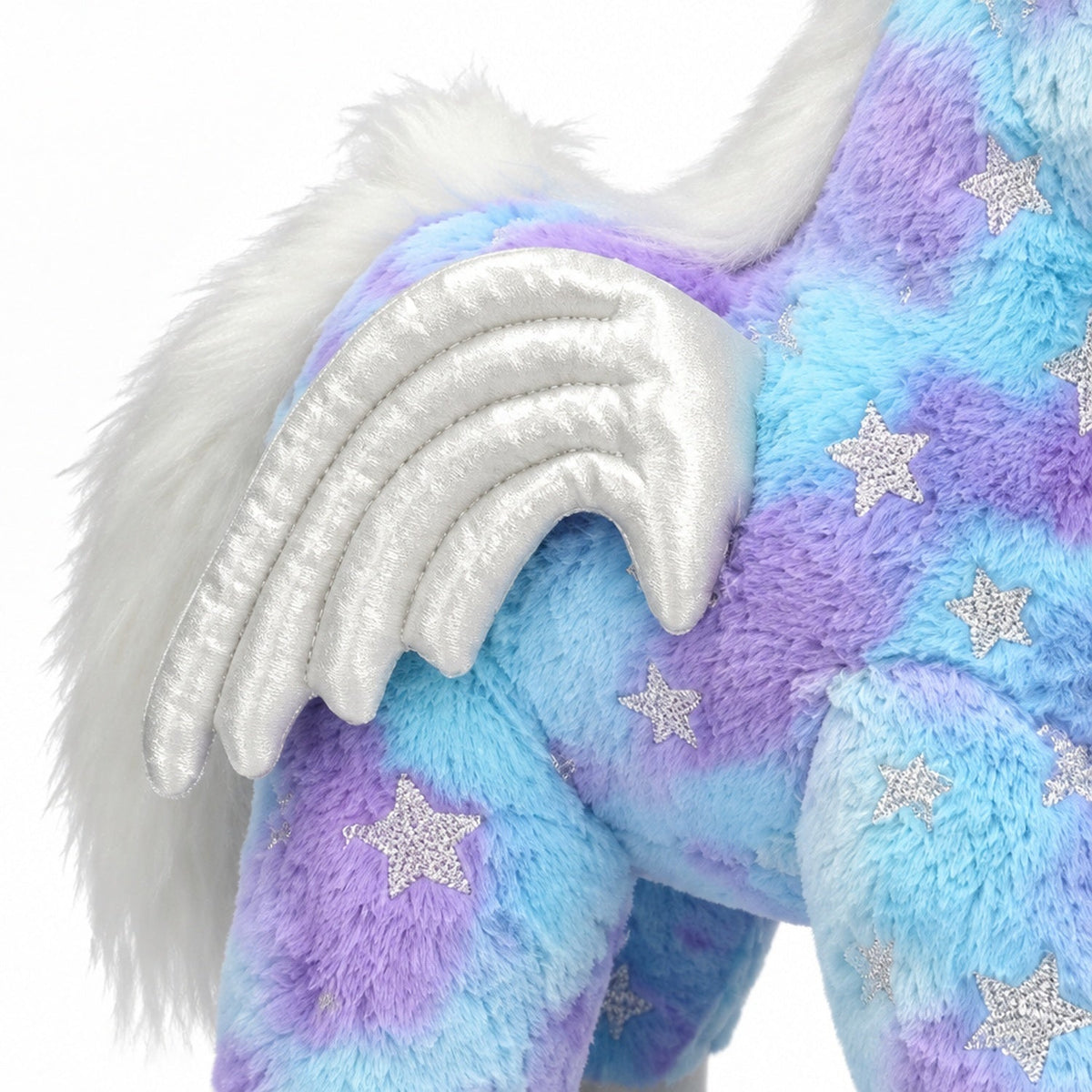 Gros plan de l'aile argentée scintillante et de la broderie étoilée de la peluche licorne bleue