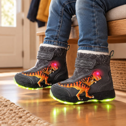 Enfant assis dans l'entrée portant les bottes de neige lumineuses grises motif dinosaure, semelle LED verte allumée